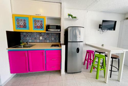 a kitchen with pink and purple cabinets and a table at Seaside Escape Studio in Cancun Beach in Cancún
