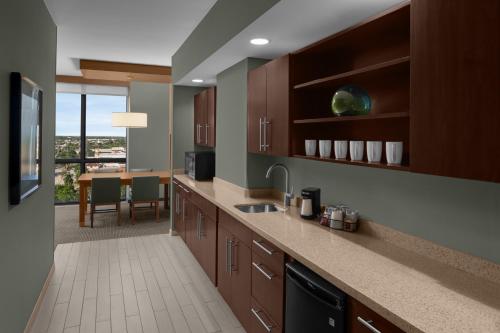 a kitchen with brown cabinets and a dining room at Hyatt Place Boca Raton in Boca Raton
