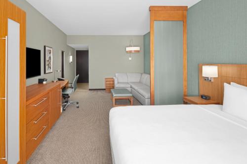 a hotel room with a bed and a living room at Hyatt Place Boca Raton in Boca Raton