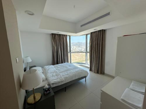 a hotel room with a bed and a large window at Apartment with Modern Amenities in Muscat