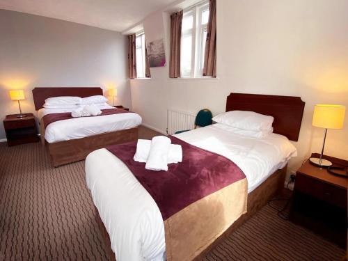 a hotel room with two beds and two lamps at Tor Park Hotel in Torquay
