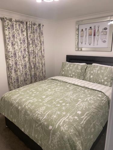 um quarto com uma cama com um edredão verde em 2Philipot em Eltham