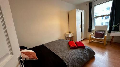 a bedroom with a bed with two red pillows on it at Cosy flat Fulham Broadway in London