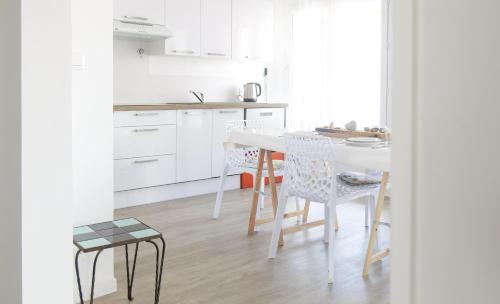 une cuisine avec des armoires blanches et une table et des chaises dans l'établissement Appartement proche océan Les Sables d'Olonne 4 personnes, à Les Sables-dʼOlonne