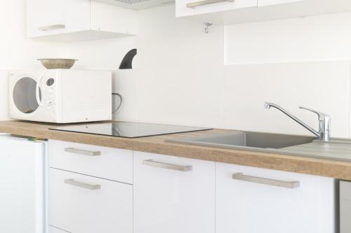 une cuisine blanche avec un évier et un micro-ondes dans l'établissement Appartement proche océan Les Sables d'Olonne 4 personnes, à Les Sables-dʼOlonne