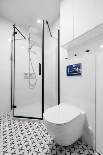 a white bathroom with a toilet and a shower at Solaris Darłówko Premium Emilia Strupiechowska in Darłowo