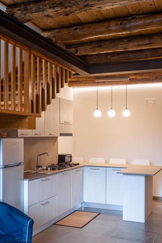 a kitchen with white cabinets and wooden ceilings at La Casa del Ciliegio in Feltre