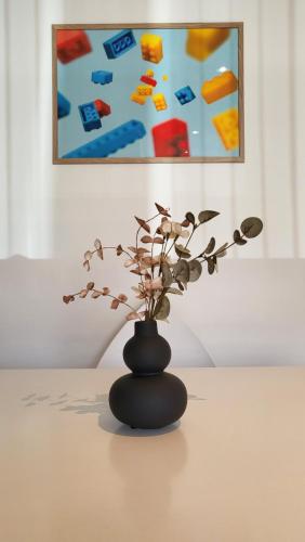 a black vase sitting on a table with a plant at Lego Fans Аpartment #1 in Billund Center in Billund