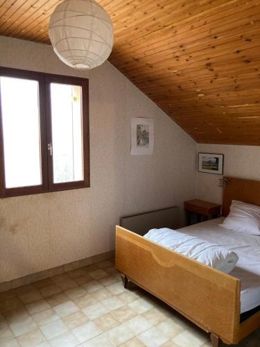 une chambre avec un lit et un plafond en bois dans l'établissement Grand chalet familial, à Forest-Saint-Julien