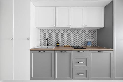 a kitchen with white cabinets and a sink at Solaris Darłówko Premium Emilia Strupiechowska in Darłowo