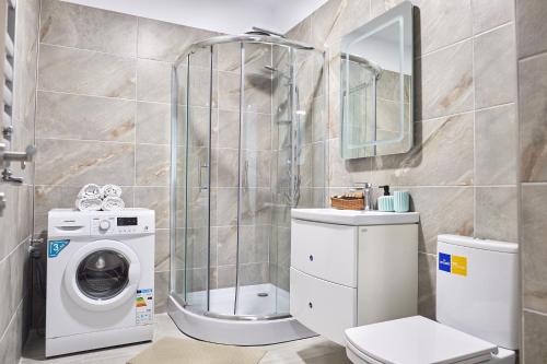 a bathroom with a shower and a washing machine at Azur 109 - Pool & Spa Beach Resort in Mamaia