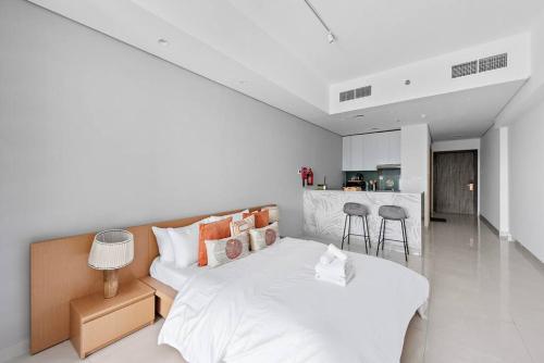 a white bedroom with a bed and a kitchen at Spacious and Cozy Apartment in Dubai