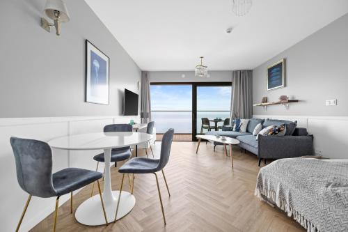 a living room with a table and chairs and a couch at Solaris Darłówko Premium Emilia Strupiechowska in Darłowo