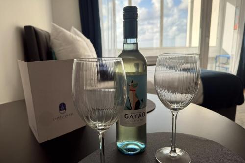 a bottle of wine and two wine glasses on a table at CuxHeaven modernes Studio-Apartment direkt am Meer mit Pool, Sauna und Massage in Cuxhaven