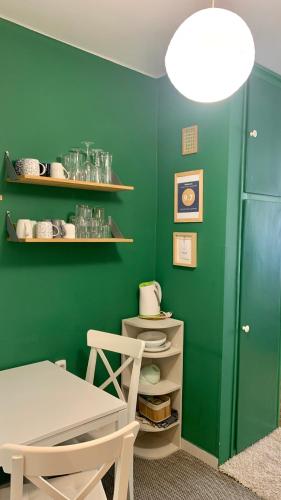 a green dining room with a table and a green wall at Mermaid house apartman in Szeged