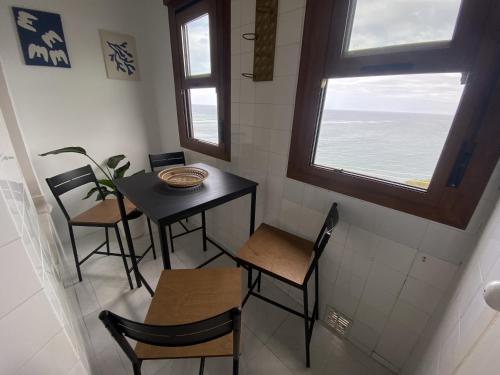 a dining room with a table and chairs and a window at Durmiendo con el mar in Lastres