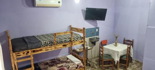 a room with two bunk beds with a table and a television at El Toro in San Fernando del Valle de Catamarca