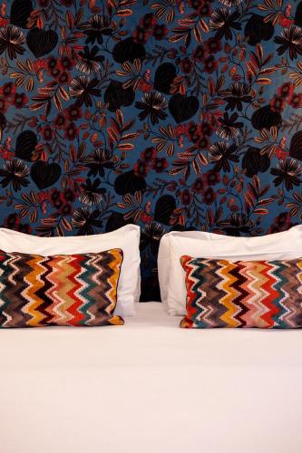 a bed with two pillows in front of a floral wallpaper at Hotel de Fleurie - Saint-Germain-des-Pres in Paris