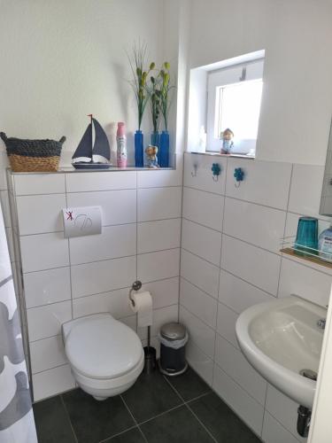 a white bathroom with a toilet and a sink at Ferienhaus Toni im Stadtkern von Bremervörde in Bremervörde