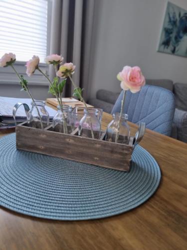 a wooden tray with vases of flowers on a table at Ferienhaus Toni im Stadtkern von Bremervörde in Bremervörde