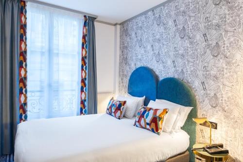 a bedroom with a bed with a blue headboard at Hotel de Fleurie - Saint-Germain-des-Pres in Paris