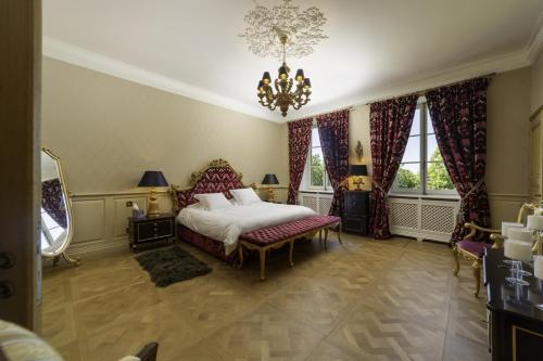 1 dormitorio con cama y lámpara de araña en Château de Berg en Cormontreuil