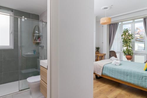 y baño con cama, ducha y aseo. en Gran casa familiar al lado de la playa en Santander