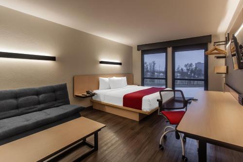 a hotel room with a bed and a couch at City Express by Marriott Celaya Galerias in Celaya