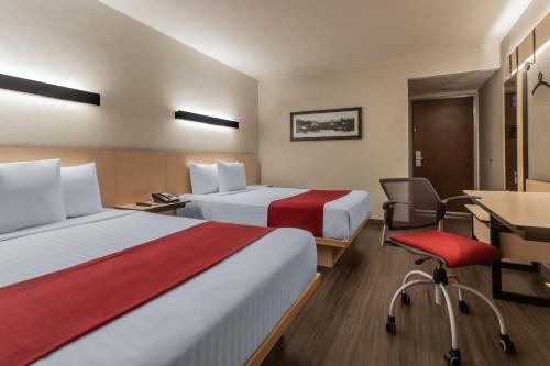 a hotel room with two beds and a desk and a chair at City Express by Marriott Celaya Galerias in Celaya