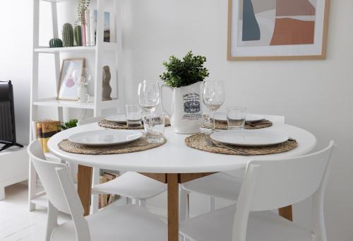 - une table à manger blanche avec des chaises et des verres blancs dans l'établissement 2ndhomes Fabianinkatu Apartments, à Helsinki