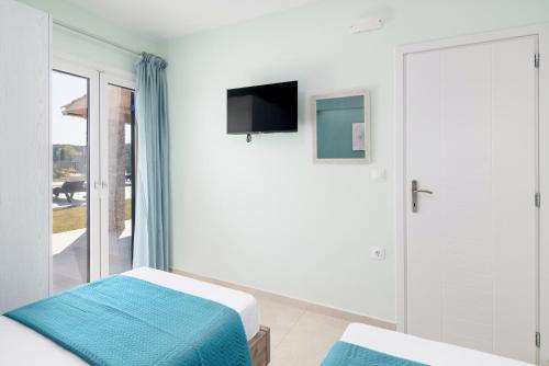 a white room with a bed and a tv at Castelia Luxury Villas in Agios Ioannis