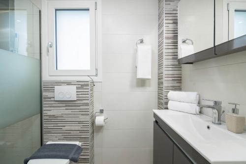 La salle de bains est pourvue d'un lavabo, de toilettes et d'une fenêtre. dans l'établissement Castelia Luxury Villas - Villa Agapi, à Ágios Ioánnis