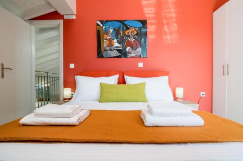 a bedroom with a bed with an orange wall at Castelia Luxury Villas in Agios Ioannis
