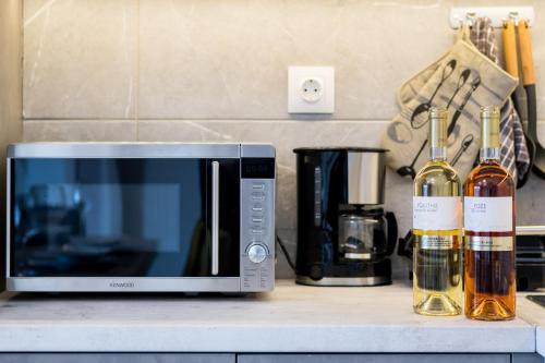 a microwave sitting on a counter next to bottles of wine at Castelia Luxury Villas in Agios Ioannis