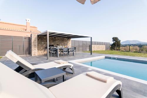 a patio with a table and chairs next to a swimming pool at Castelia Luxury Villas in Agios Ioannis
