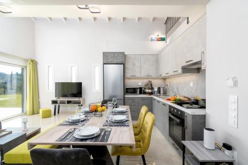a kitchen with a wooden table and yellow chairs at Castelia Luxury Villas in Agios Ioannis