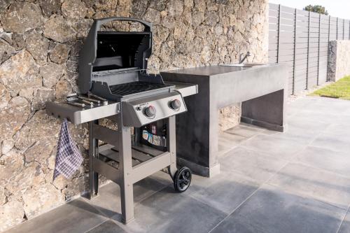 a barbecue grill sitting next to a stone wall at Castelia Luxury Villas in Agios Ioannis