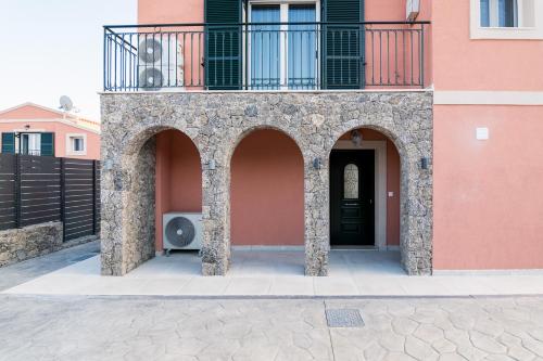 a pink building with a balcony and a black door at Castelia Luxury Villas in Agios Ioannis