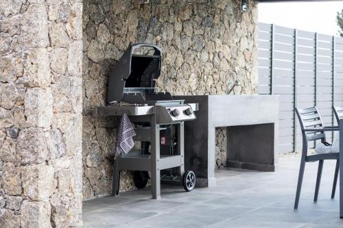 a barbecue grill sitting next to a stone wall at Castelia Luxury Villas in Agios Ioannis