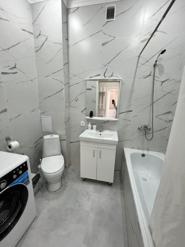 uma casa de banho branca com um lavatório, um WC e uma banheira em ЖК Грант Чемпион em Astana