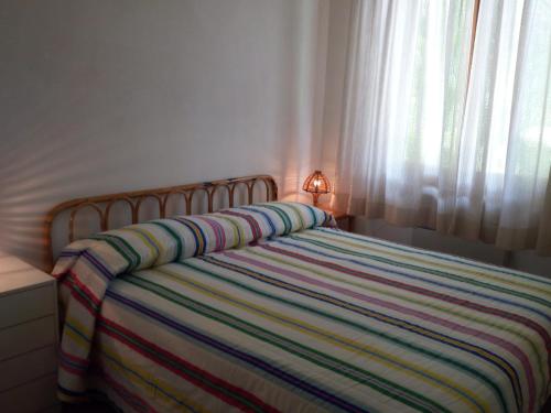 a bedroom with a bed with a colorful striped blanket at Villetta Pescespada in Grosseto