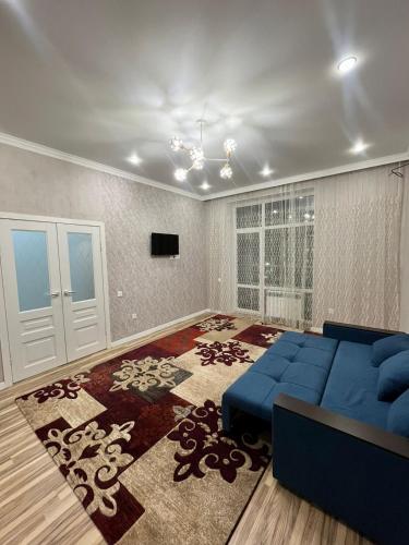 uma sala de estar com um sofá azul e um tapete em ЖК Грант Чемпион em Astana
