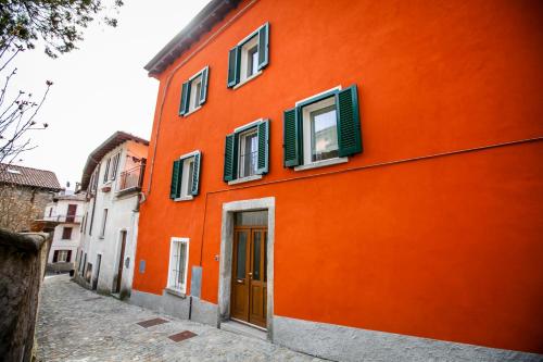 an orange building with green shutters on a street at Casa di Bruno in Pellio Superiore