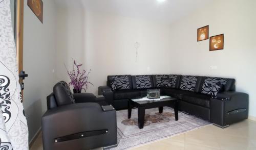 a living room with a black couch and a table at Vila Dean in Berat