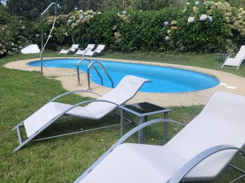 un grupo de sillas blancas sentadas junto a una piscina en Aldea Lamacido en Loiba