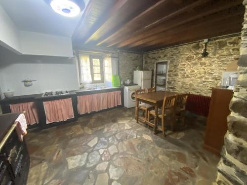 eine Küche mit einem Tisch und einer Steinmauer in der Unterkunft Aldea Lamacido in Loiba