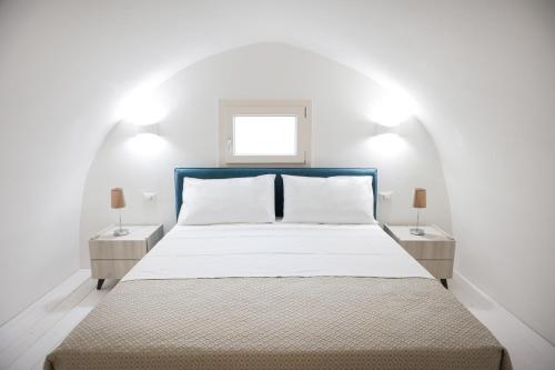 a white bedroom with a bed and two night stands at B&B LE DUE CORTI in Matino