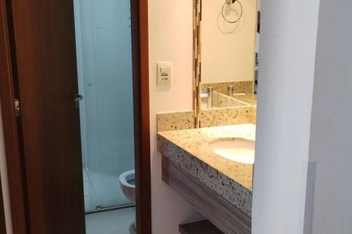 een badkamer met een wastafel, een spiegel en een toilet bij Apartamento Privê Riviera 10 in Caldas Novas