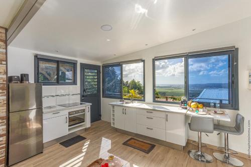 a kitchen with white cabinets and windows with a view at Chalet étoilé BAYALOCATION in Le Lamentin