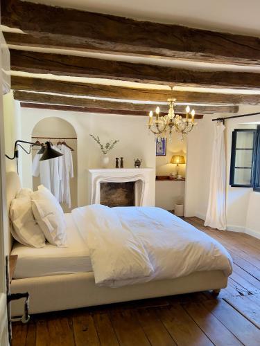 ein Schlafzimmer mit einem weißen Bett und einem Kamin in der Unterkunft Maison G.H. in Champniers-et-Reilhac